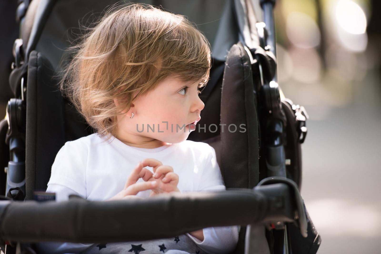 little and very beautiful baby girl sitting in the pram and waiting for mom