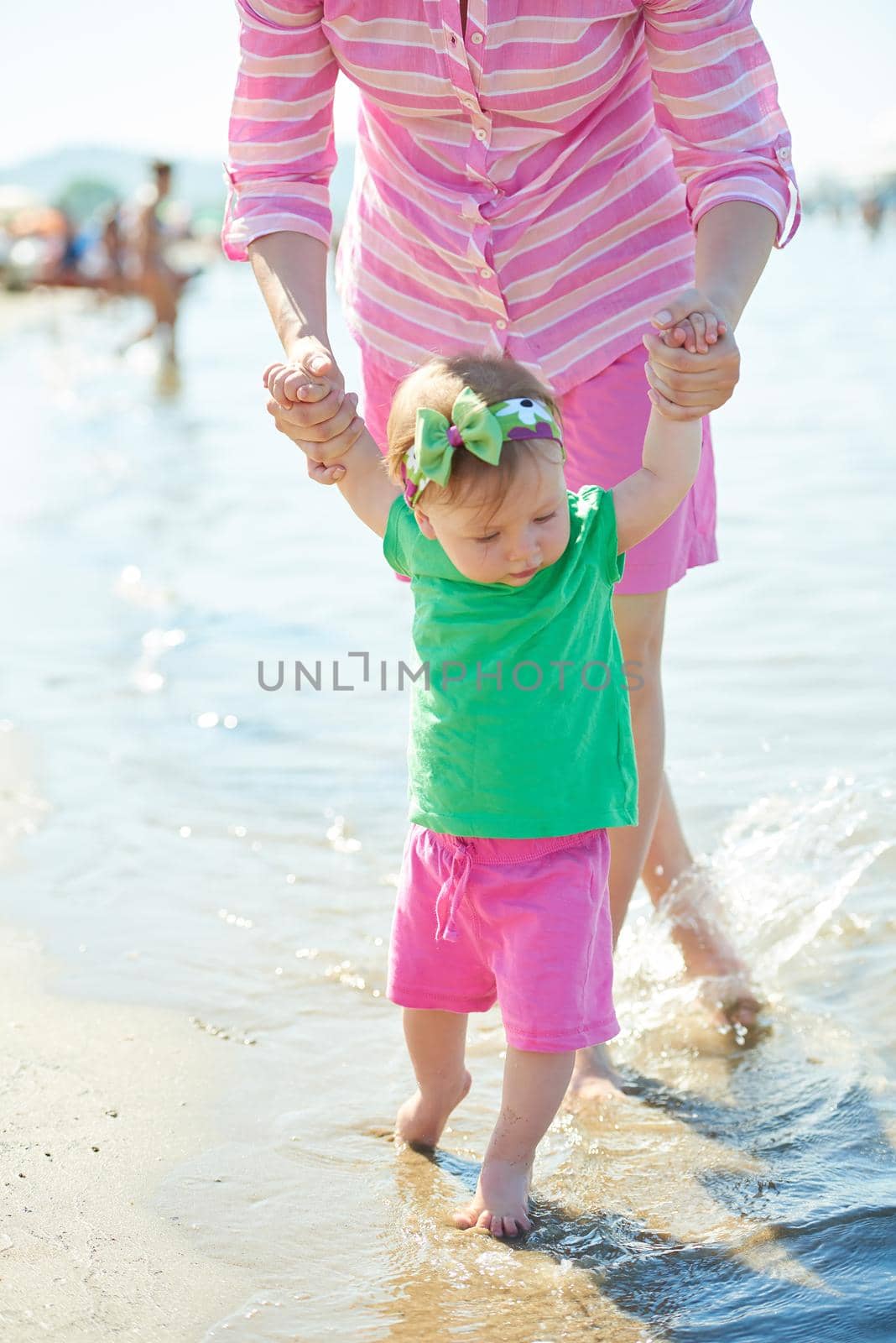 happy mom and baby on beach  have fun while learning to walk and  make first steps