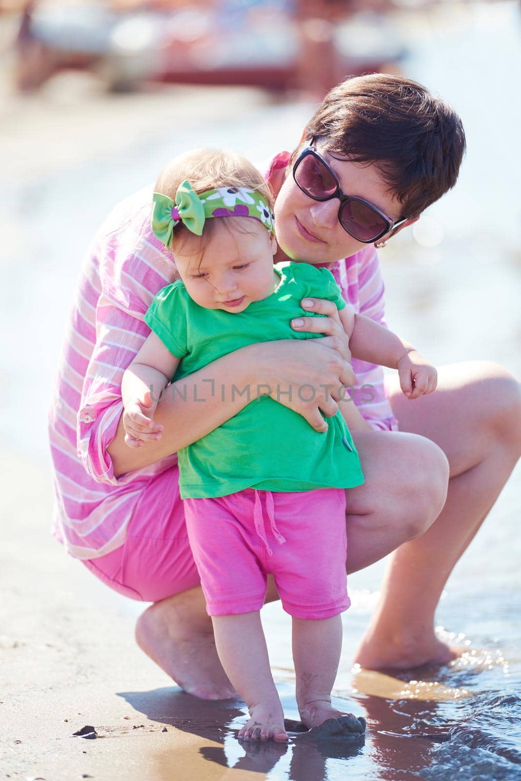 happy mom and baby on beach  have fun while learning to walk and  make first steps