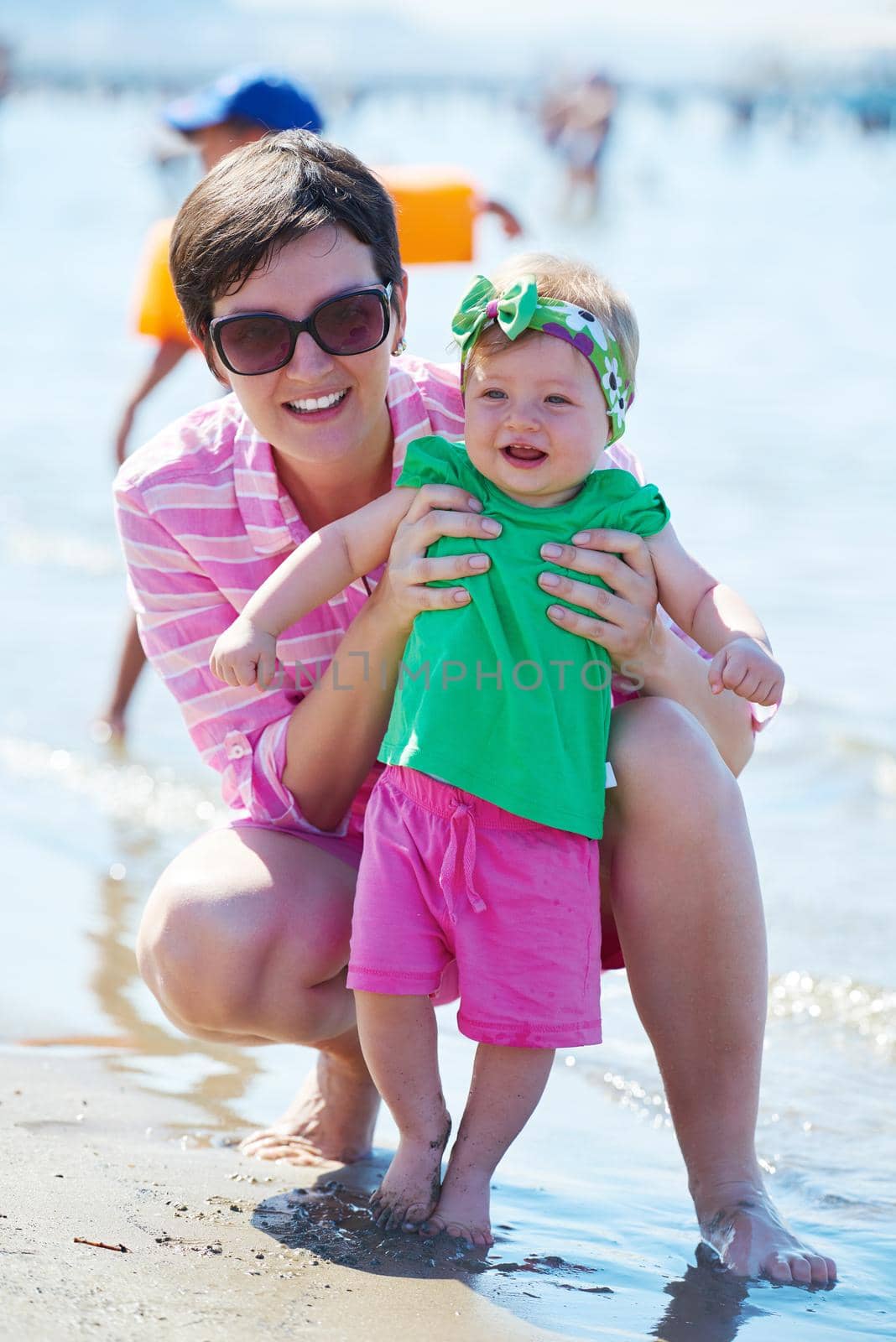 happy mom and baby on beach  have fun while learning to walk and  make first steps