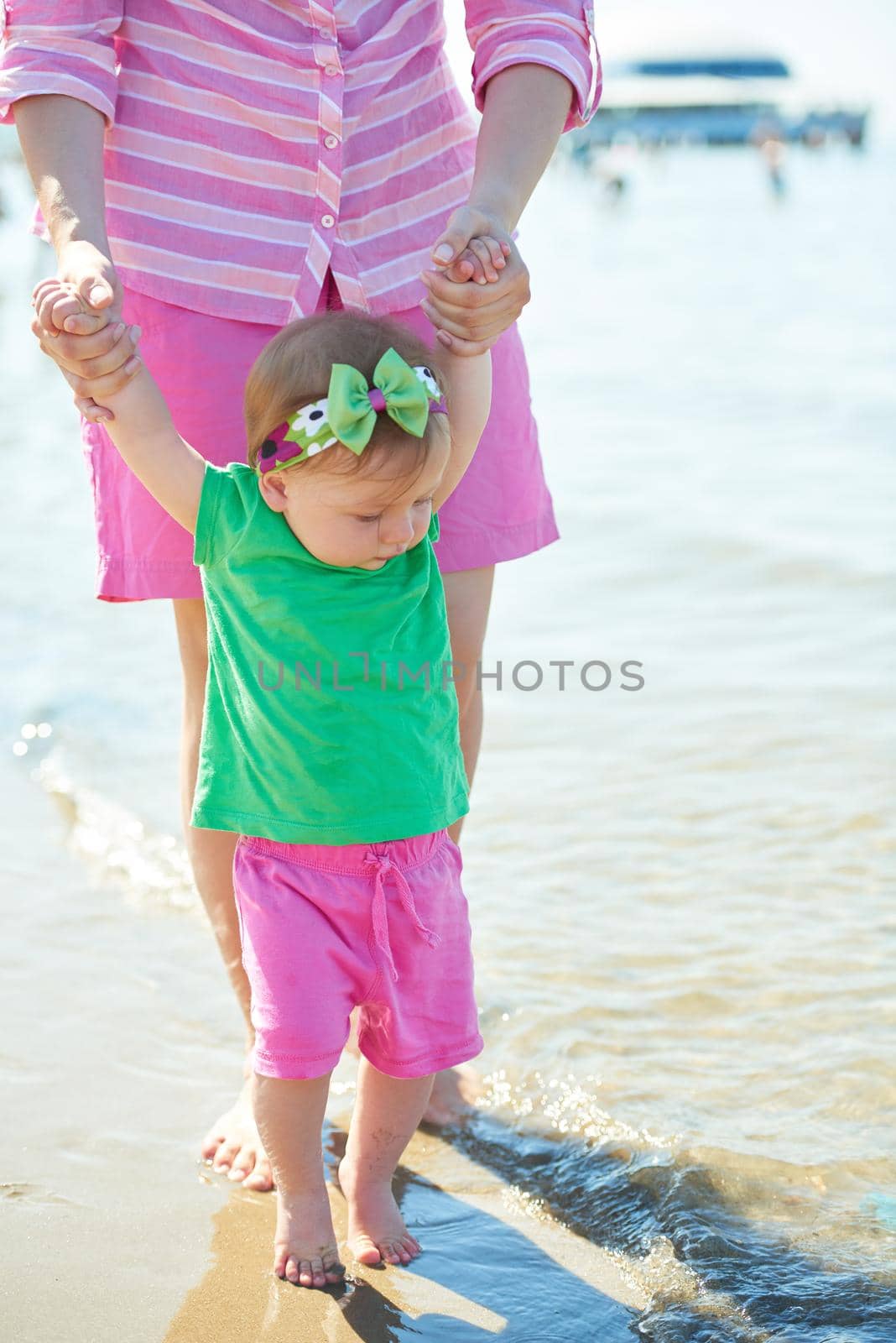 happy mom and baby on beach  have fun while learning to walk and  make first steps