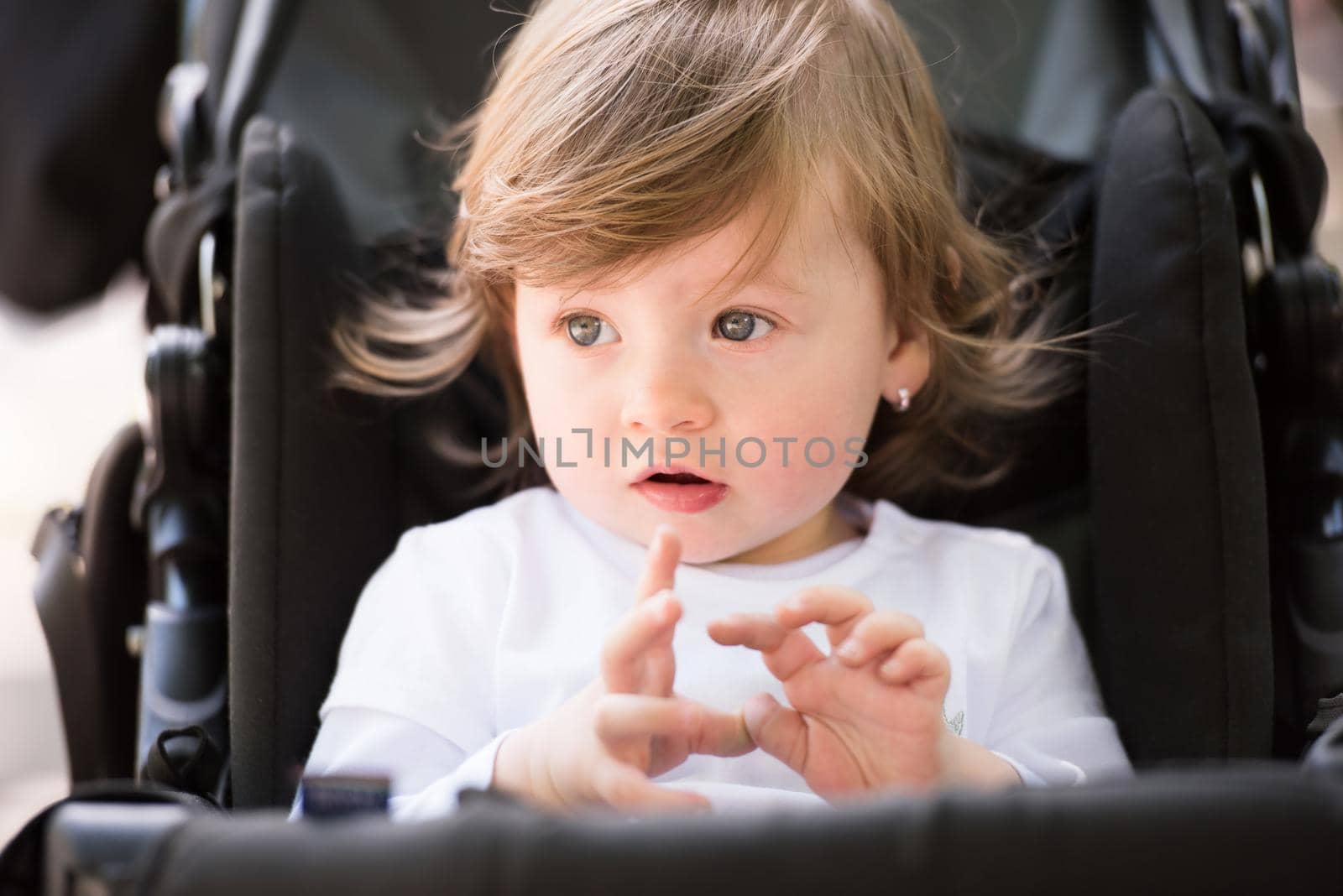 little and very beautiful baby girl sitting in the pram and waiting for mom