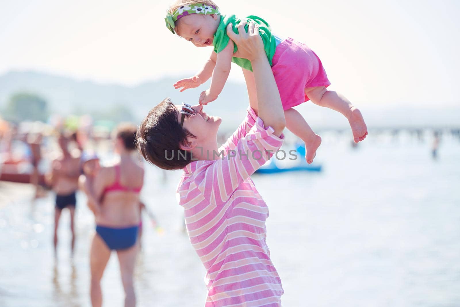 happy mom and baby on beach  have fun while learning to walk and  make first steps