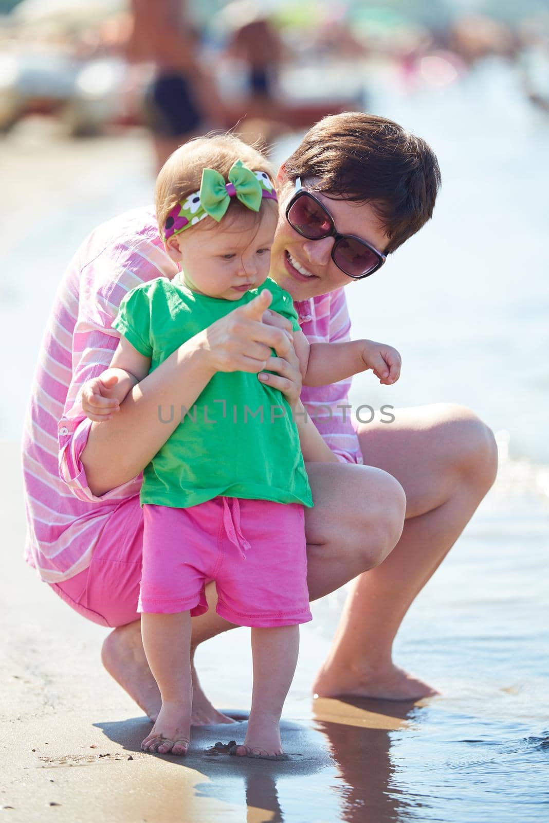 happy mom and baby on beach  have fun while learning to walk and  make first steps