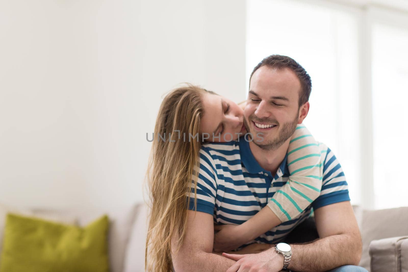 young handsome couple enjoys hugging on the sofa in their luxury home villa