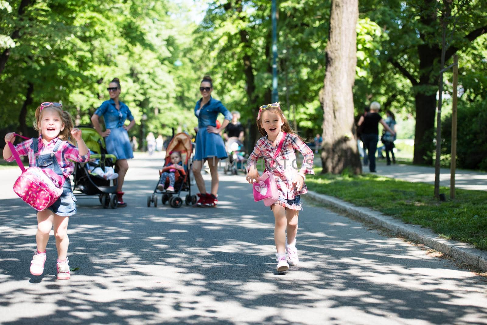 Young beautiful twins mother with children enjoying a sunny day in city park