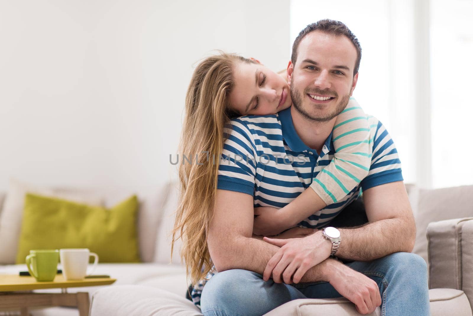 young handsome couple enjoys hugging on the sofa in their luxury home villa