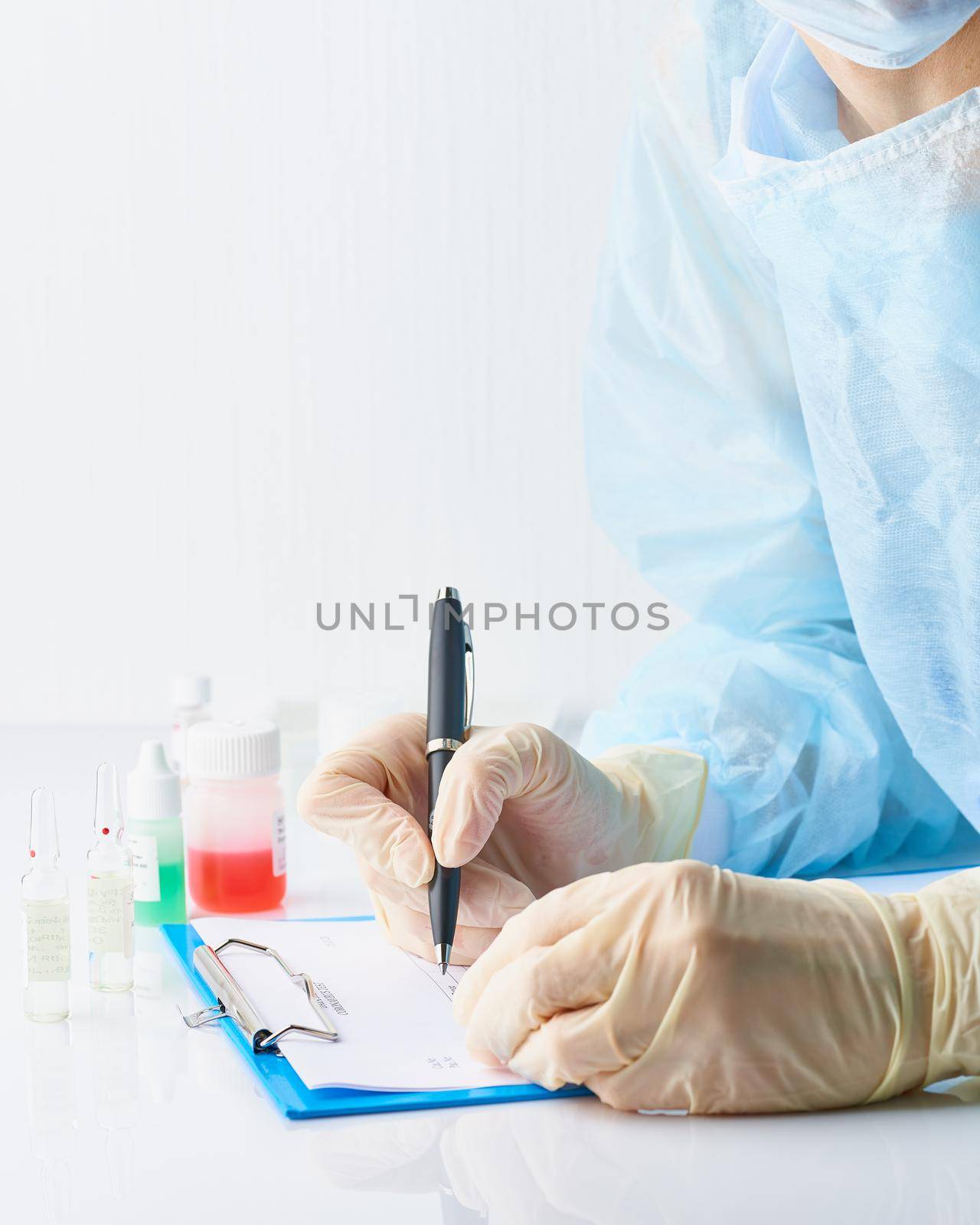 Pandemic COVID-19, Coronavirus. Doctor in hospital is on duty, avail for work, filling out forms. Woman in uniform and face mask conducts tests in laboratory, writes down results. Selective focus