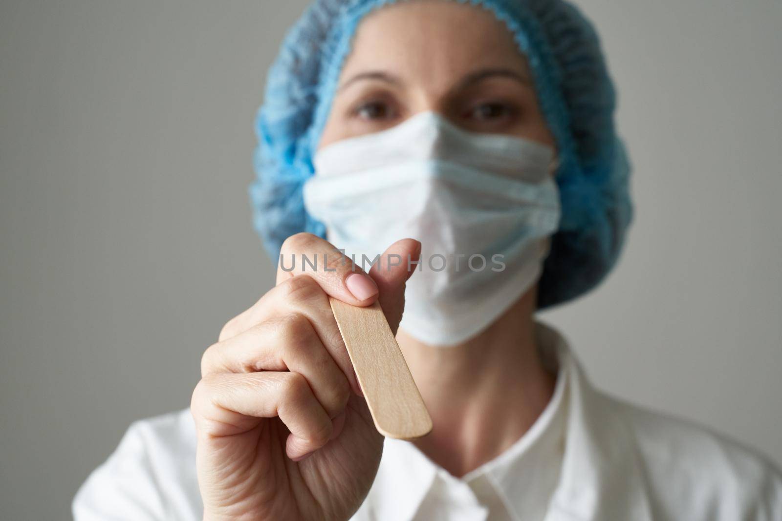 Female doctor in medical mask and uniform check up condition of throat. Illness and Covid-19 protection, medical safety. Close up