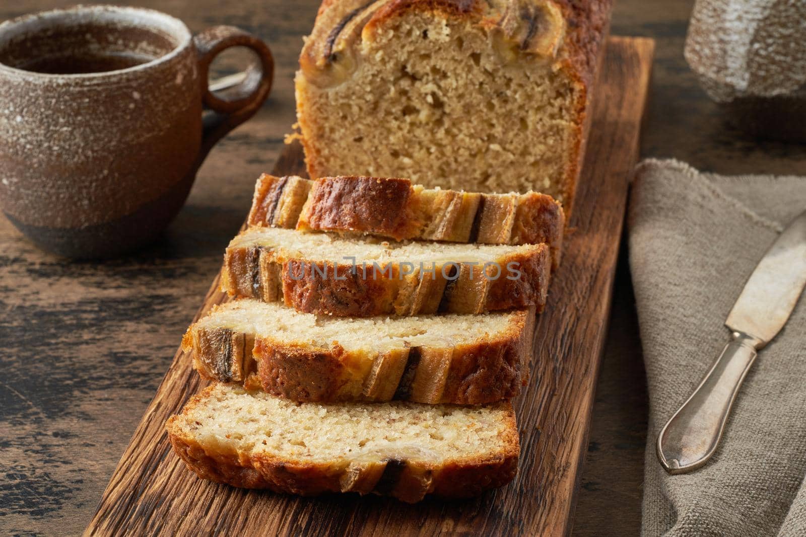 Banana bread. Cake with banana, traditional american cuisine. Slices of loaf. Dark background, black table.