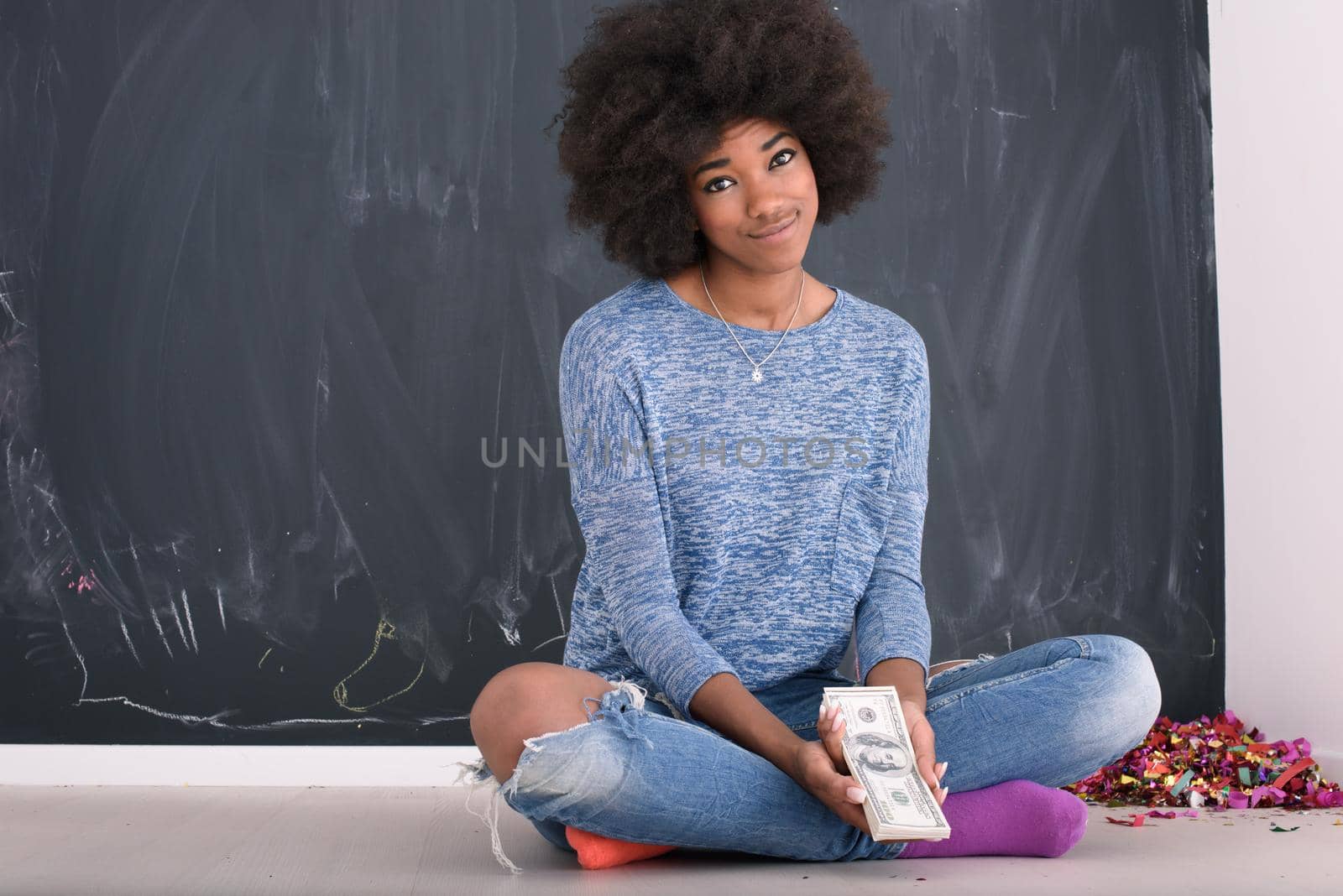Portrait of a beautiful smiling afro american woman holding money isolated on a gray background