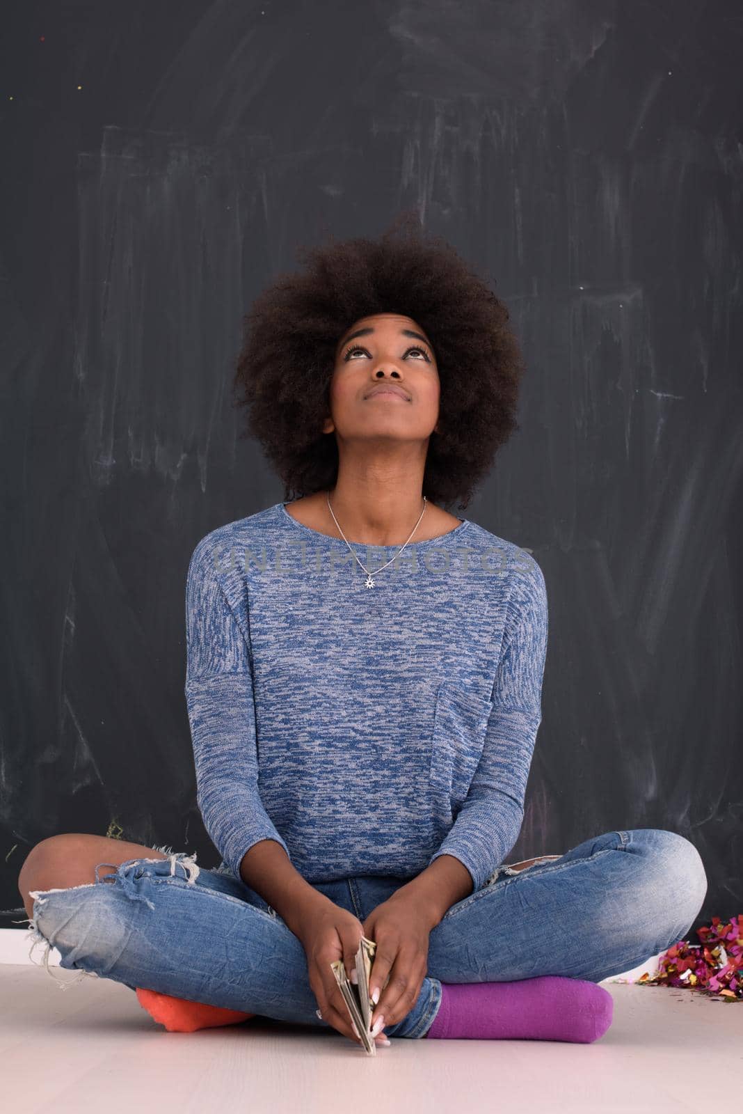 portrait of a beautiful friendly African American woman with a curly afro hairstyle and lovely smile sitting isolated on a gray background