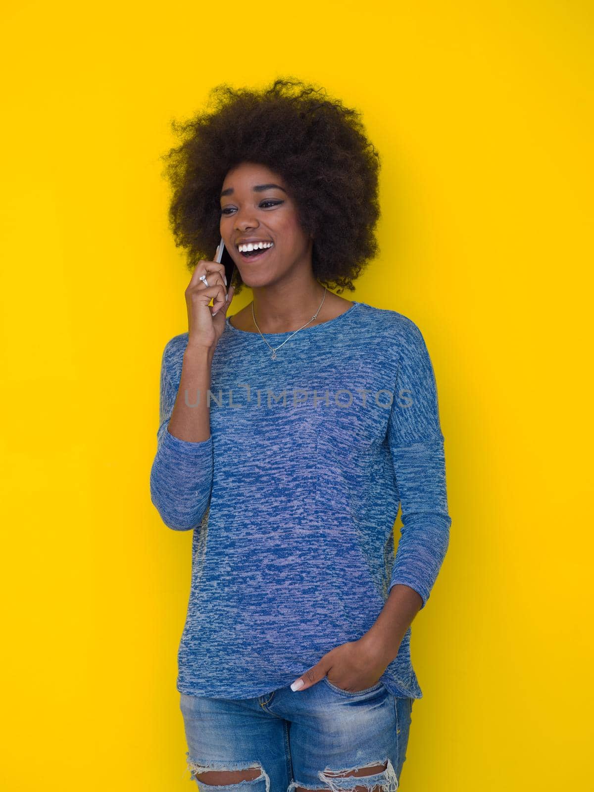 Young Happy African American Woman Using mobile phone  Isolated on a yellow background