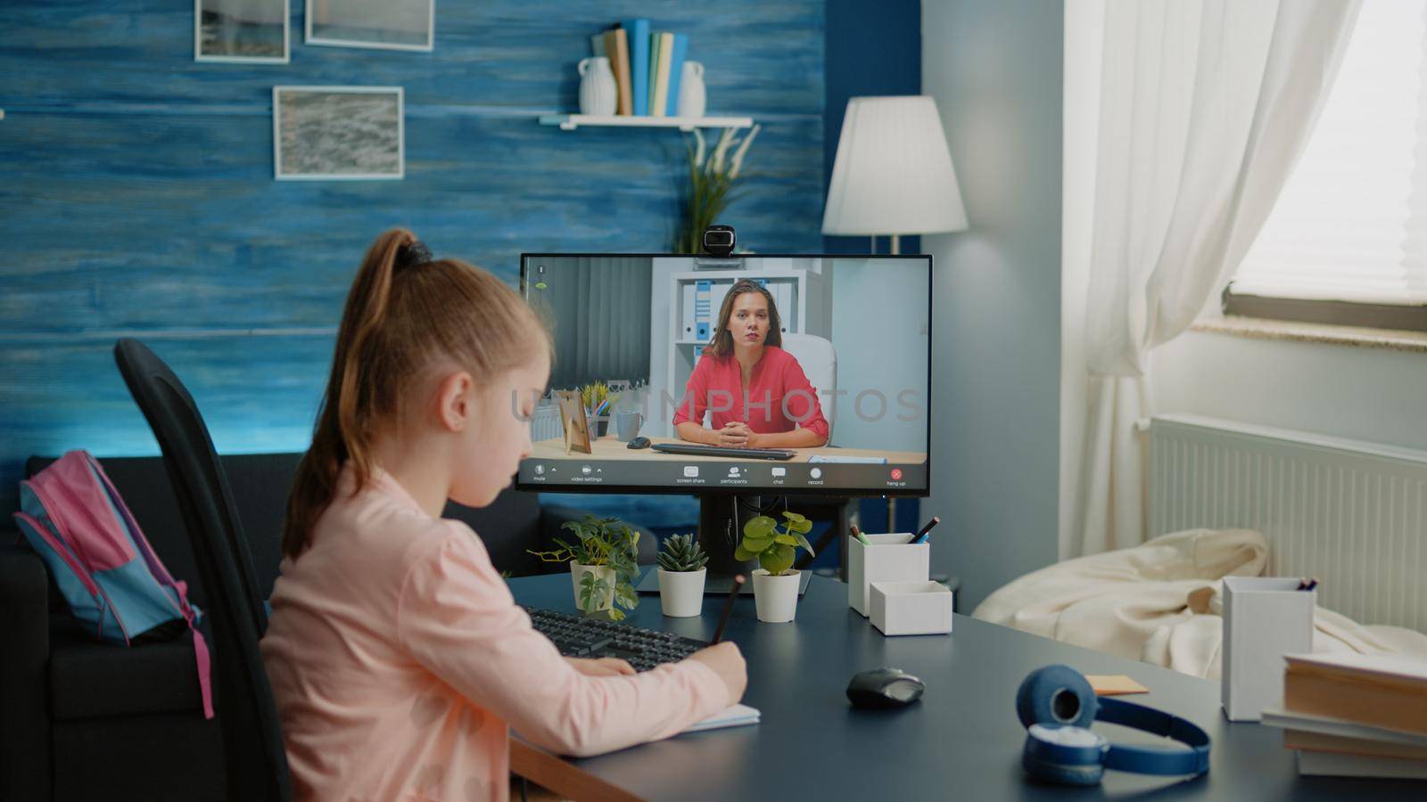 Schoolgirl and teacher using video call for remote lessons and courses on computer from home. Little child using video conference with professor for online class work and teaching information