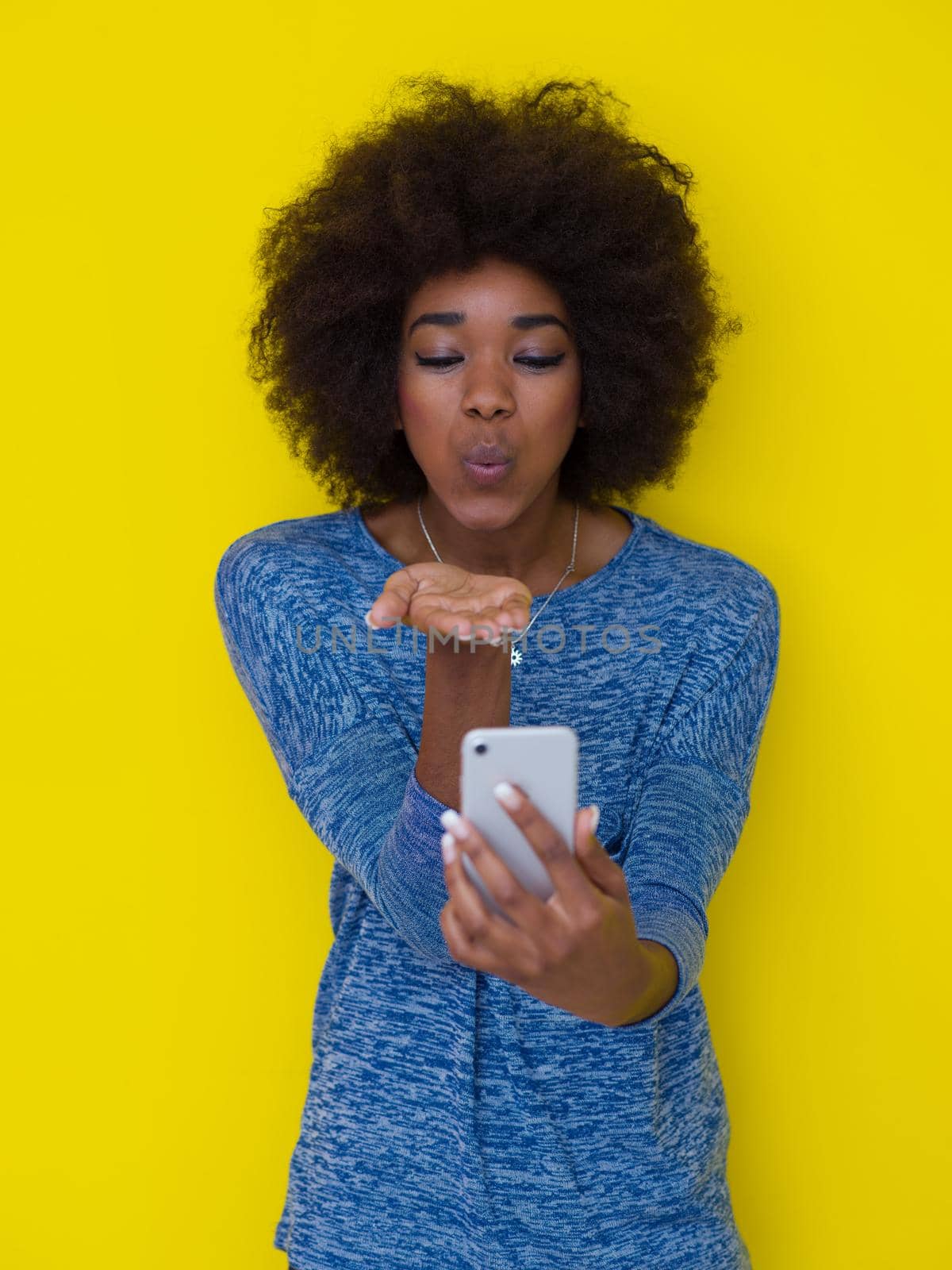 Young Happy African American Woman Using mobile phone  Isolated on a yellow background