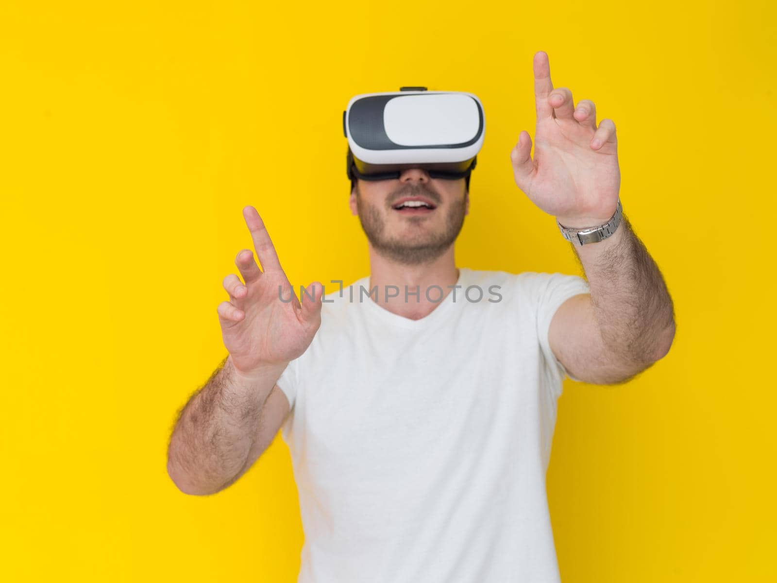Happy man getting experience using VR headset glasses of virtual reality, isolated on yellow background