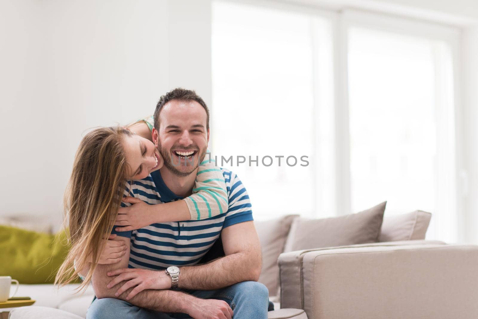 young handsome couple enjoys hugging on the sofa in their luxury home villa