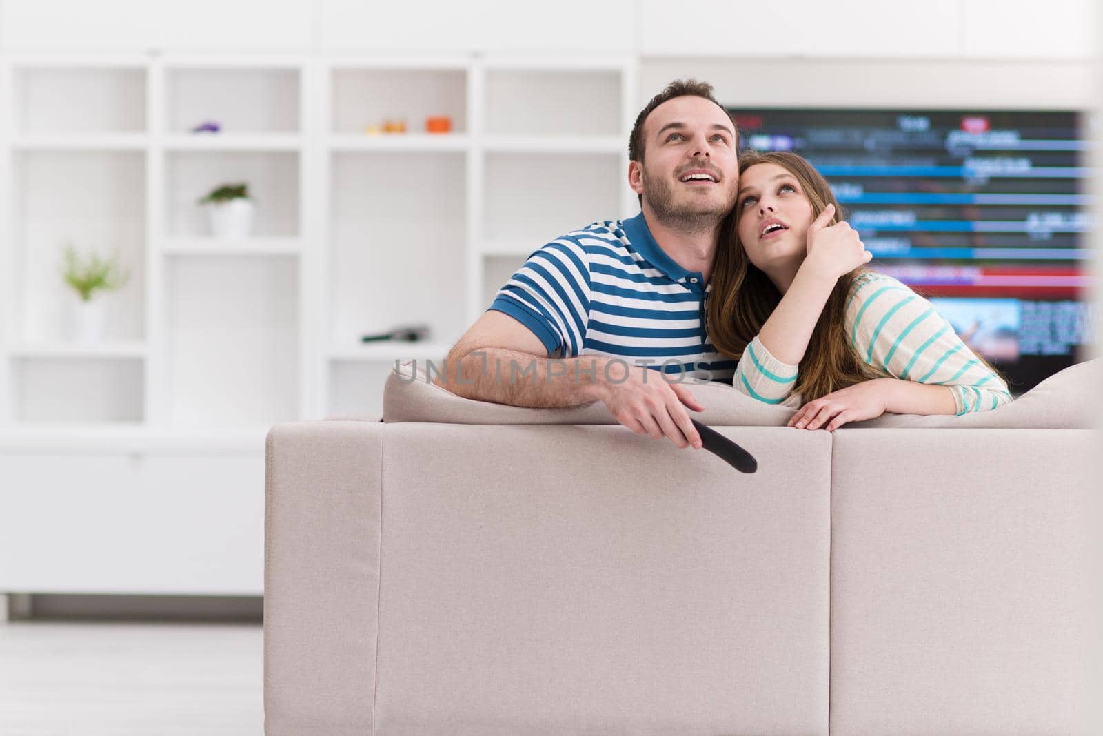 Young couple on the sofa watching television together in their luxury home