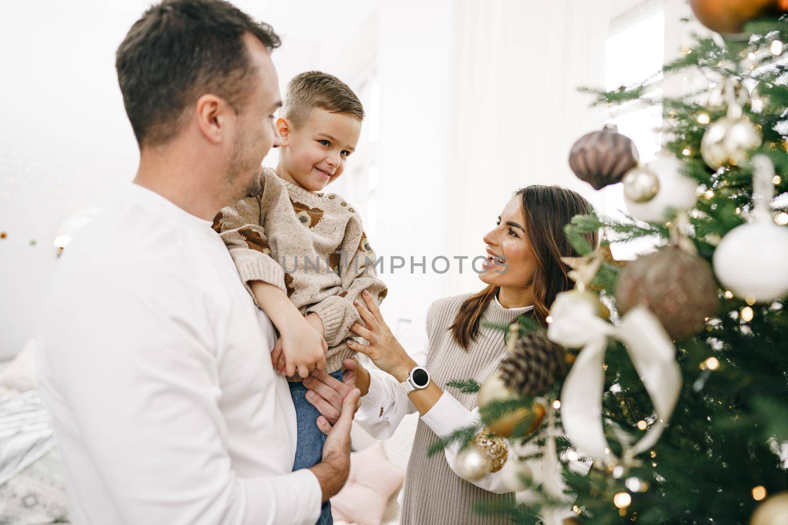 Family of 3 decorating a Christmas tree at home, close up