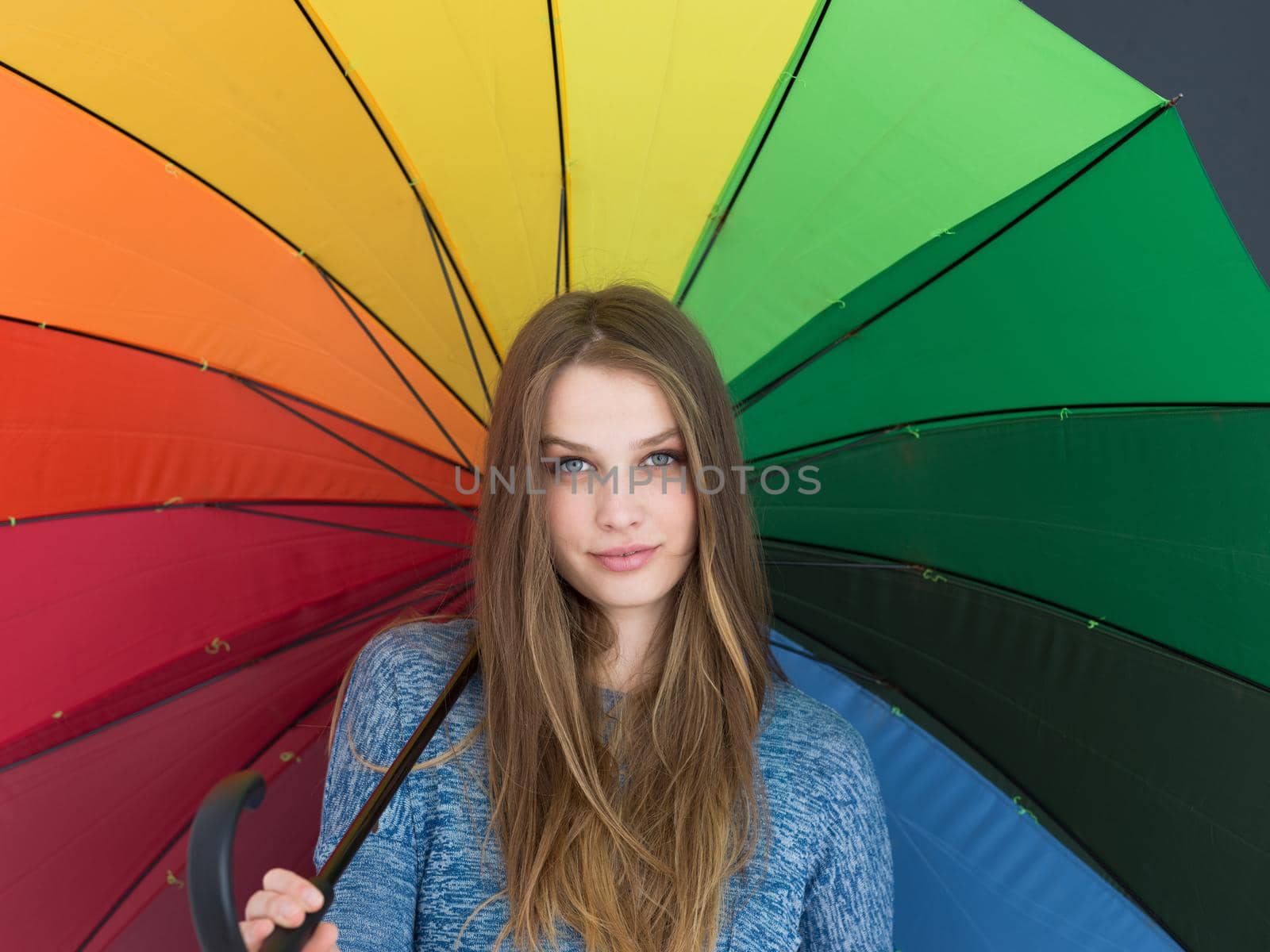 portrait of a young handsome woman with a colorful umbrella isolated on a gray background