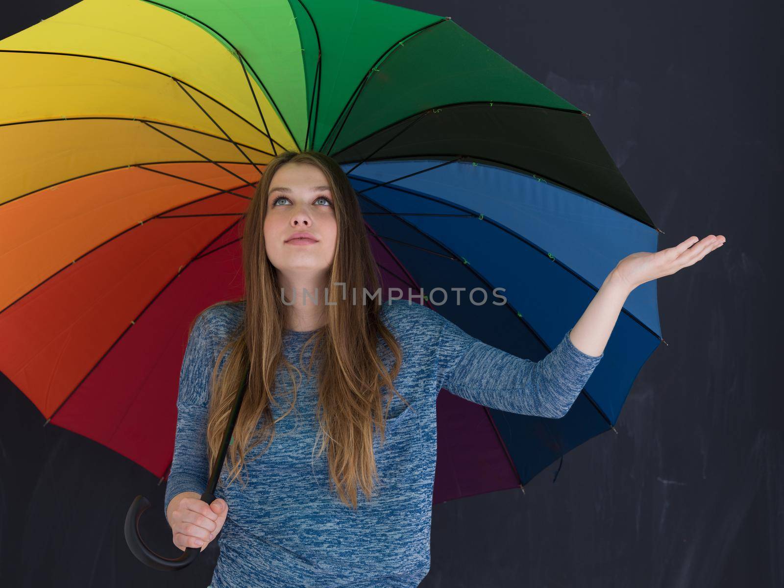 portrait of a young handsome woman with a colorful umbrella isolated on a gray background