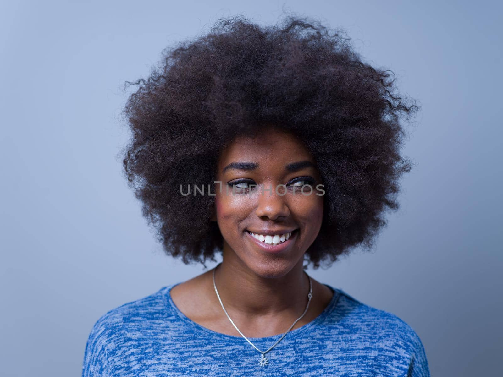 portrait of a beautiful friendly African American woman with a curly afro hairstyle and lovely smile isolated on a gray background