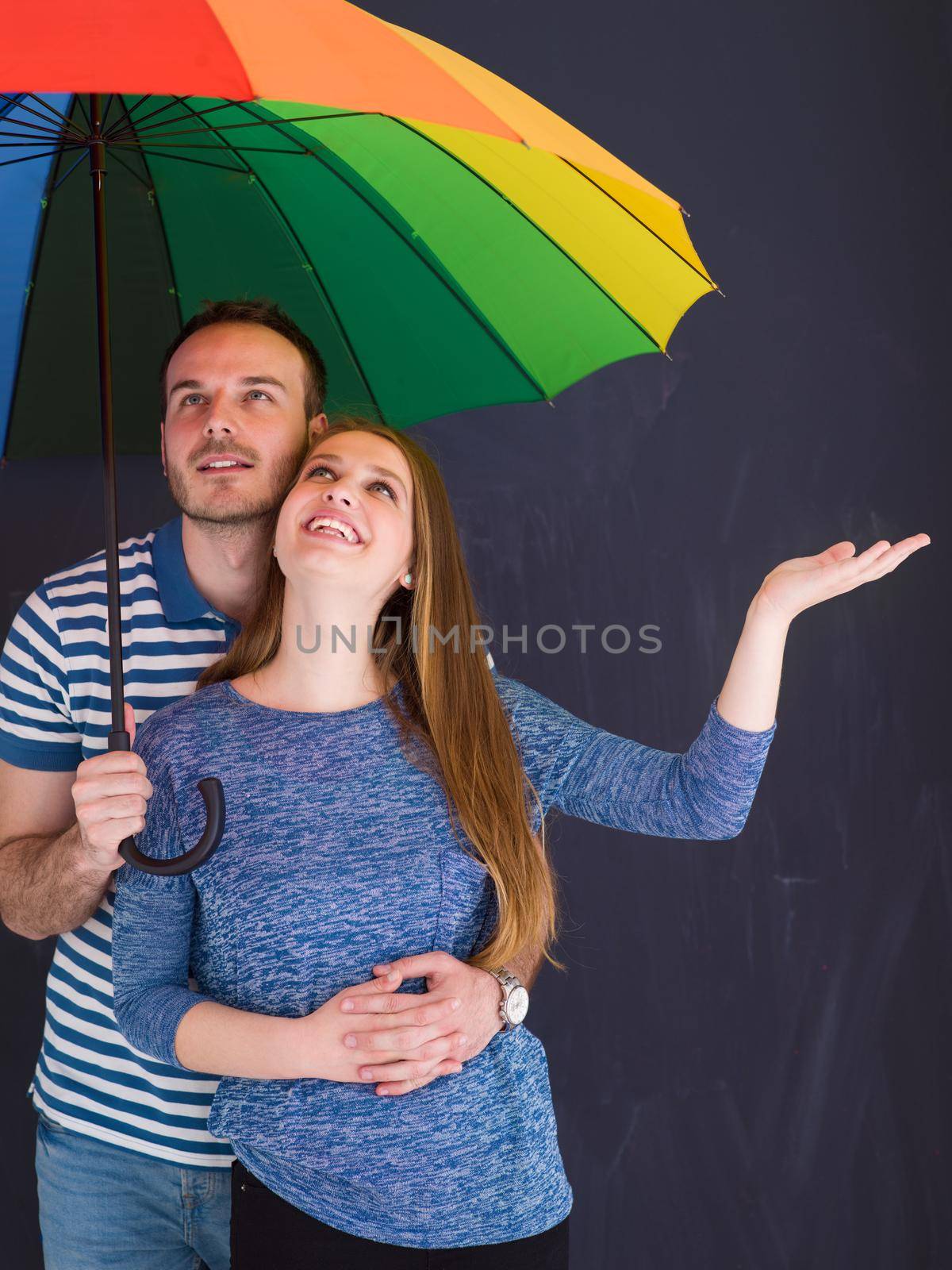 portrait of a beautiful loving young couple with a colorful umbrella isolated on a gray background