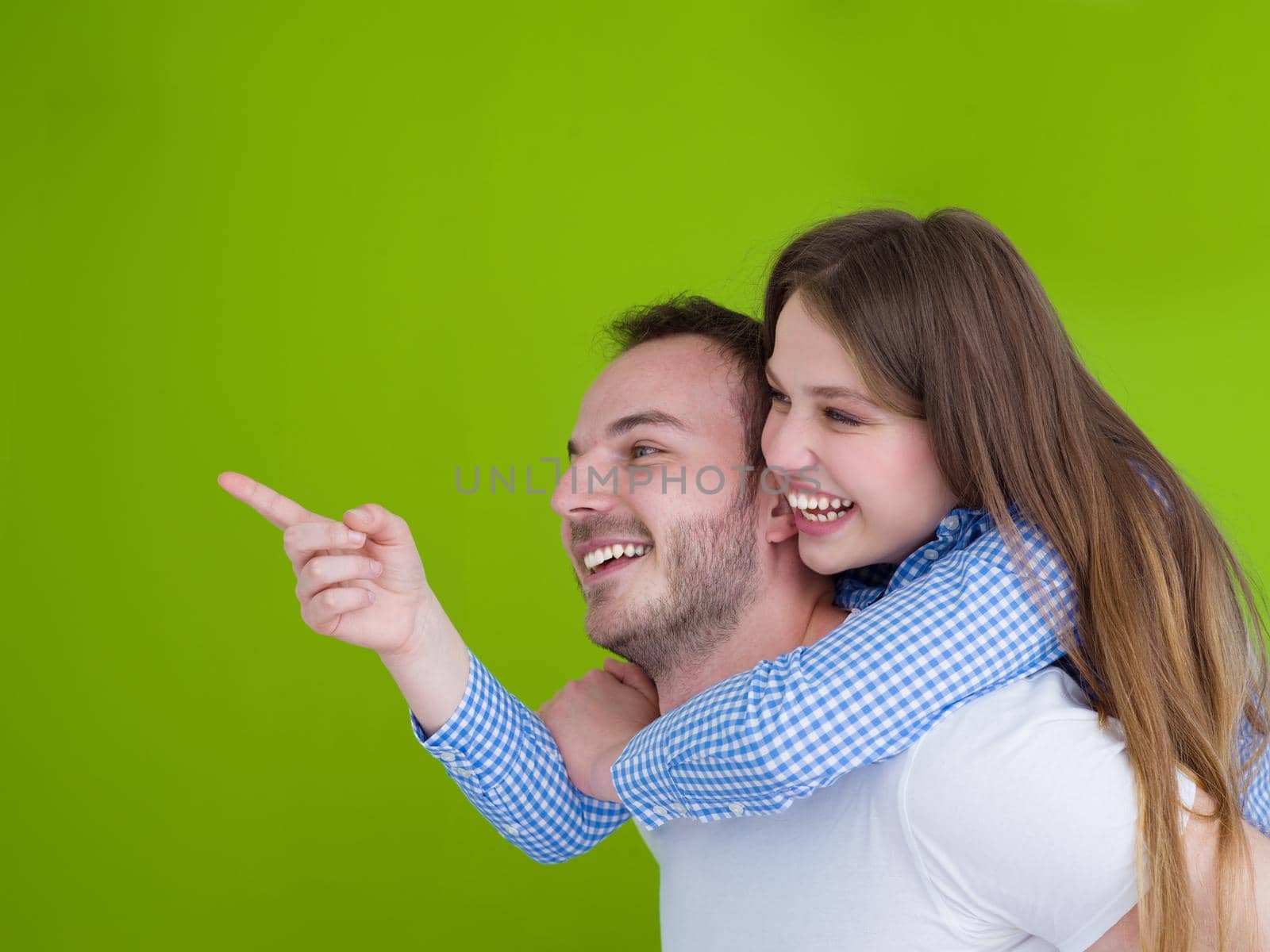 happy young man piggybacking his girlfriend isolated on green background
