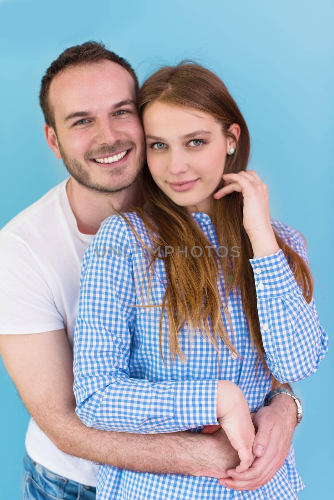 portrait of happy young loving couple looking at camera isolated on blue Background