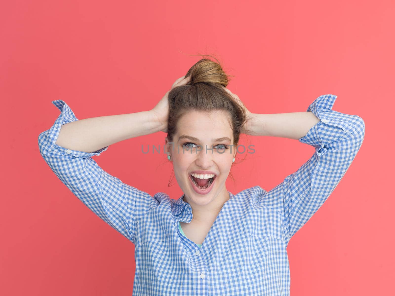Portrait of a beautiful positive young woman while playing with her long silky hair isolated on red background