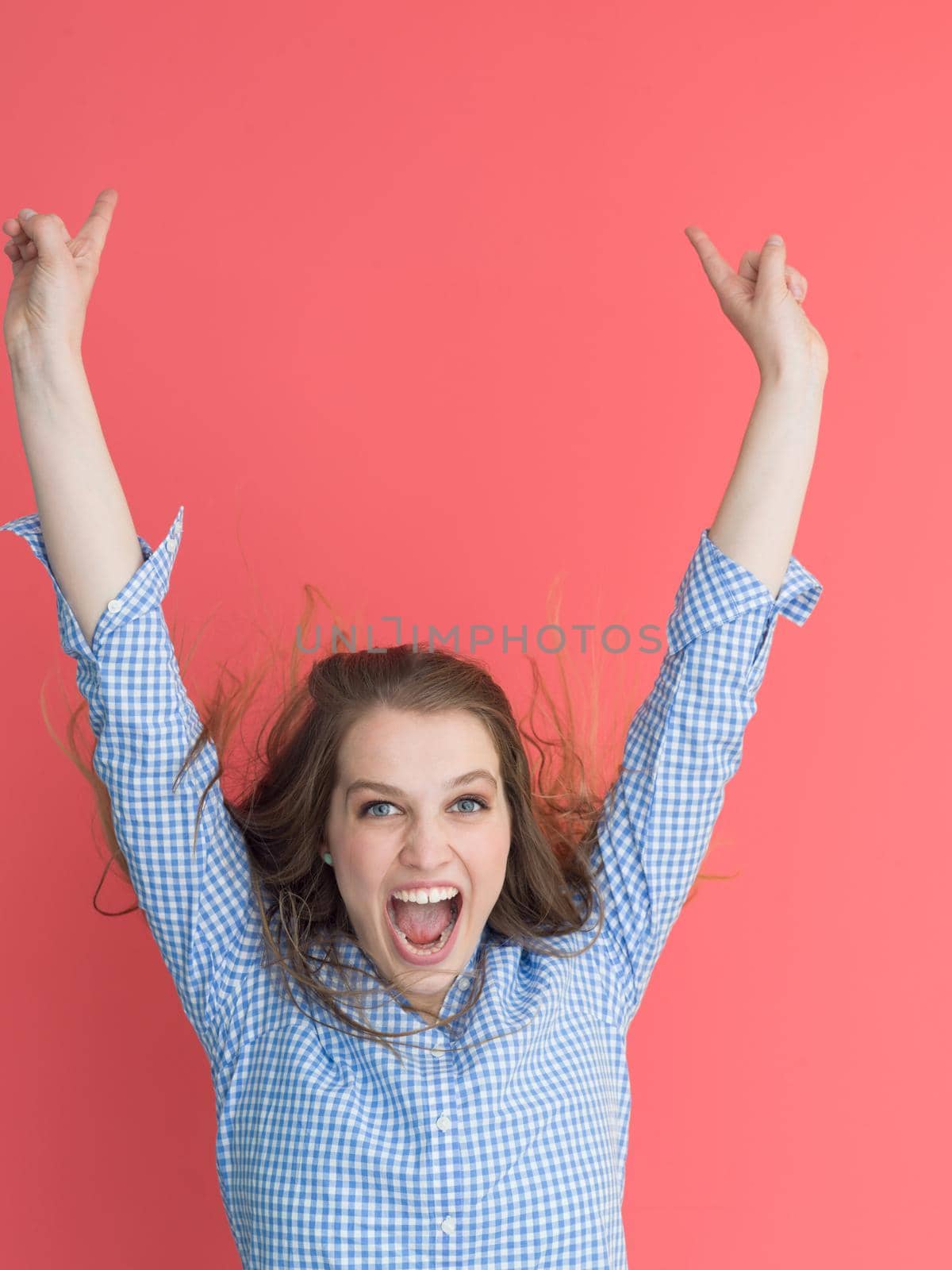Portrait of a beautiful positive young woman while playing with her long silky hair isolated on red background