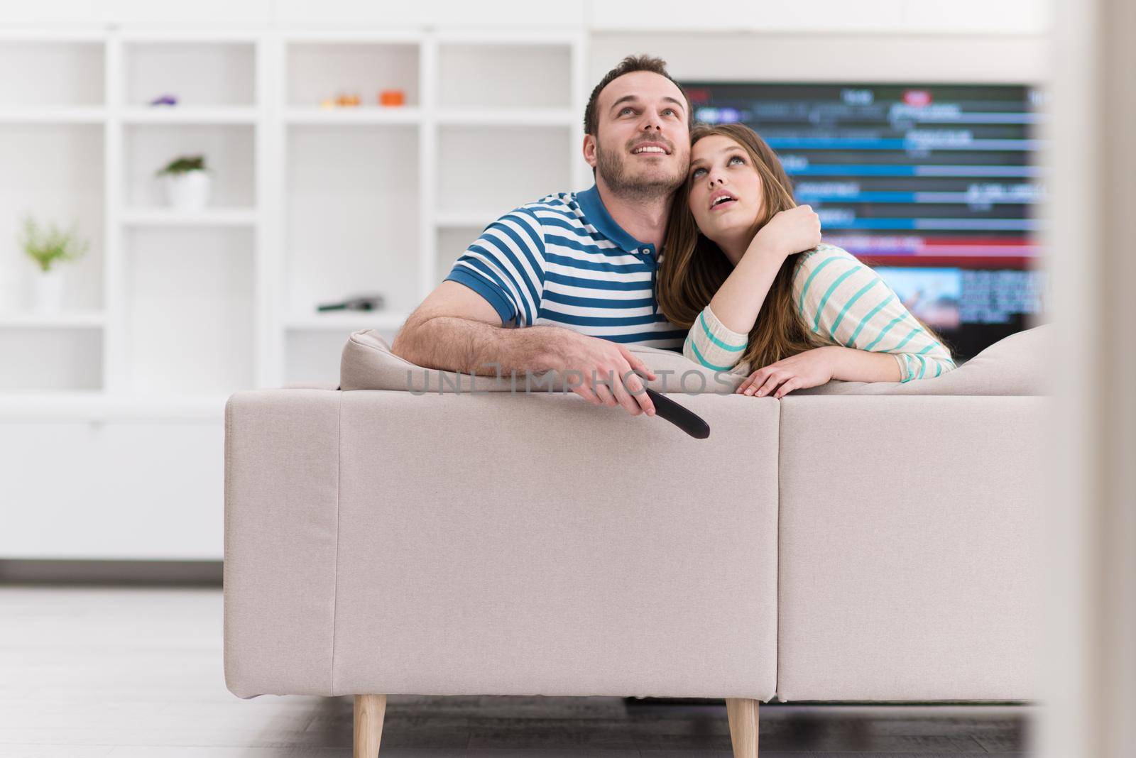 Young couple on the sofa watching television together in their luxury home