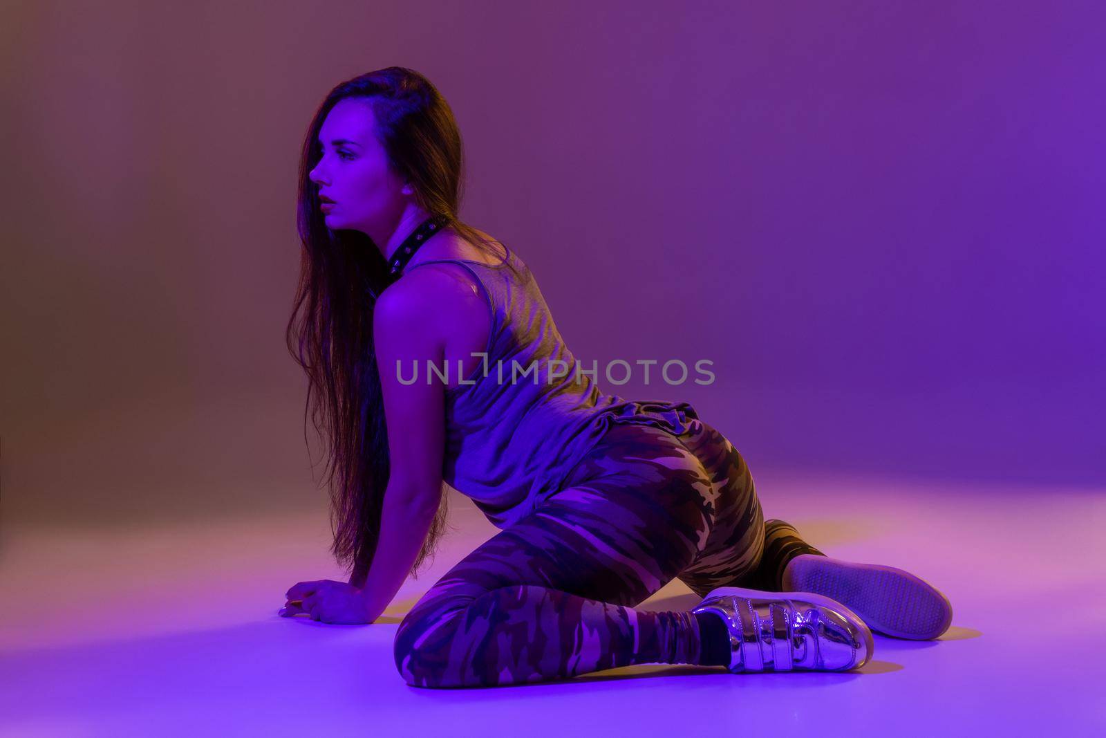 Attractive young blonde woman in the studio dancing Booty dance on a pink background. Color filters