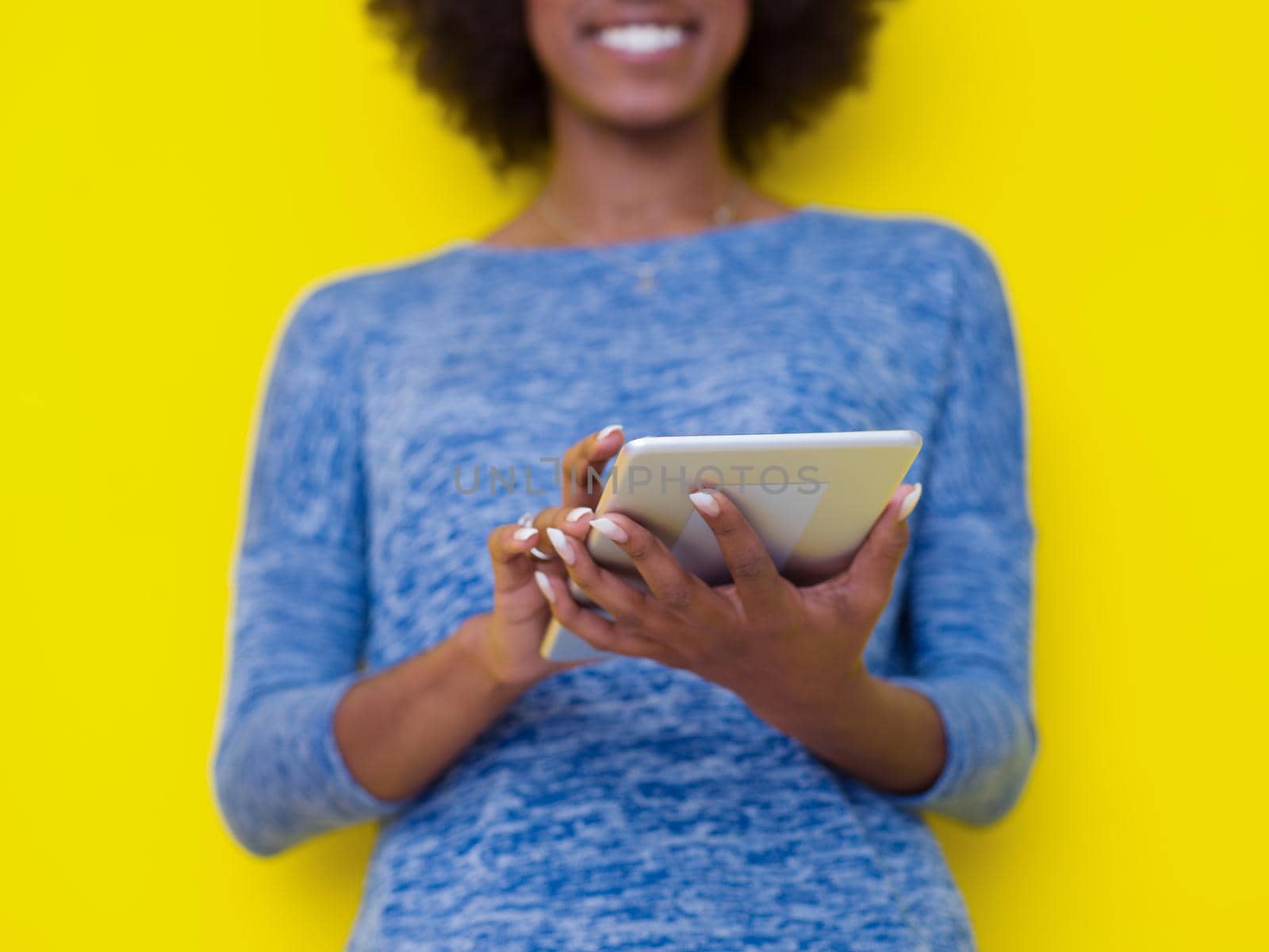 Young Happy African American Woman Using Digital Tablet  Isolated on a yellow background