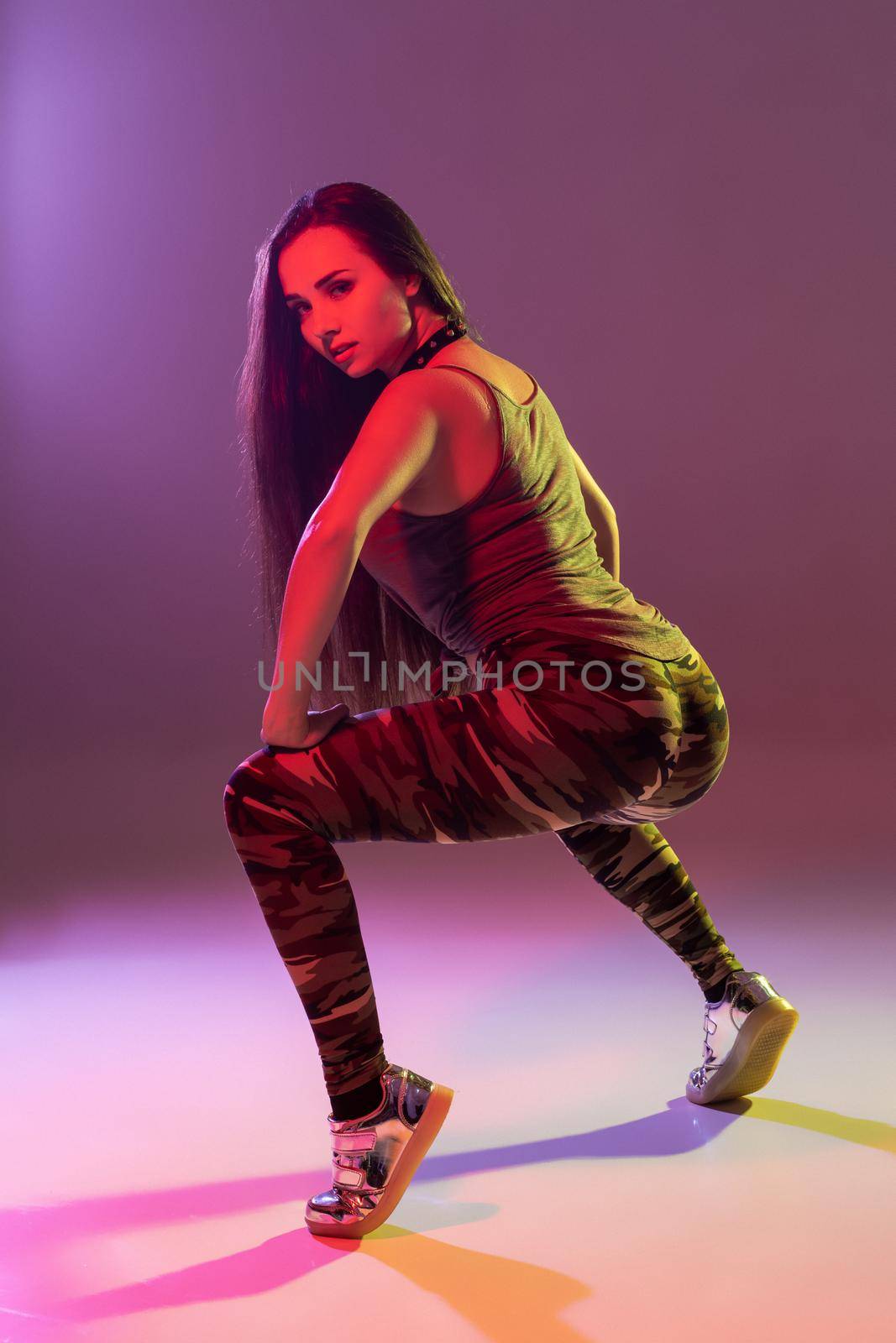 Attractive young blonde woman in the studio dancing Booty dance on a pink background. Color filters
