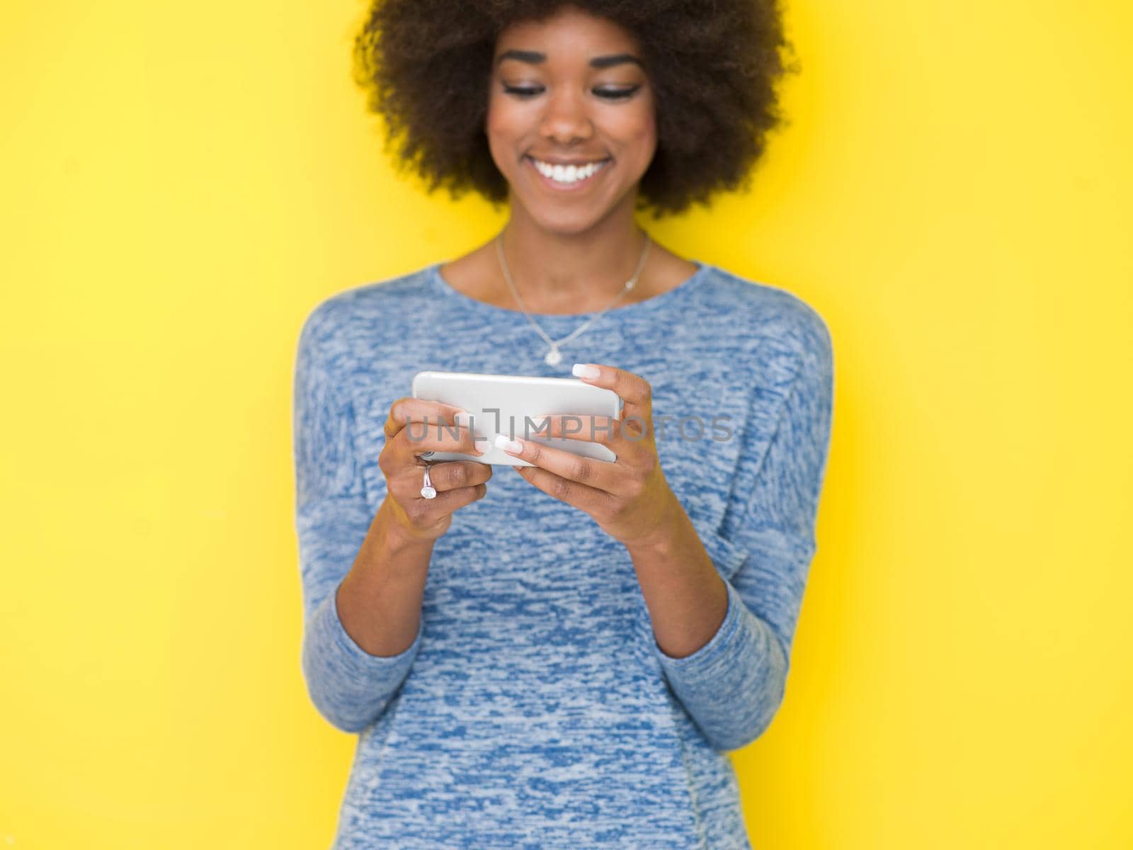 Young Happy African American Woman Using mobile phone  Isolated on a yellow background
