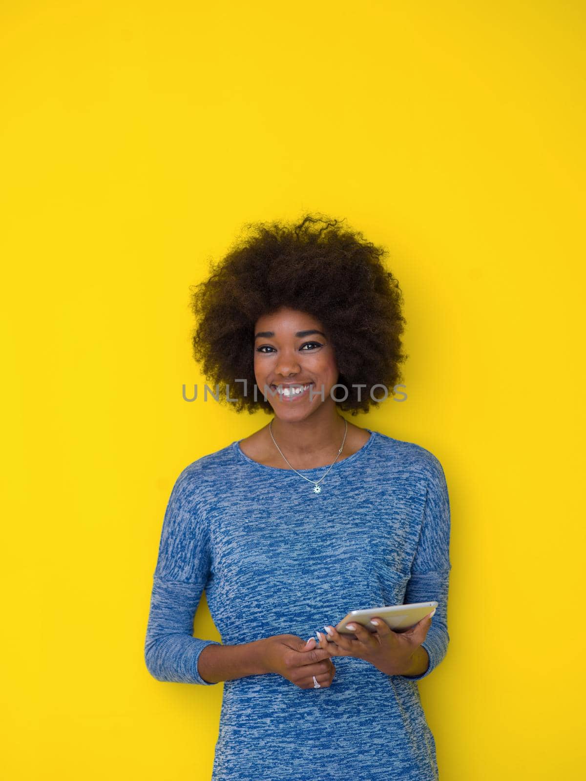 Young Happy African American Woman Using Digital Tablet  Isolated on a yellow background