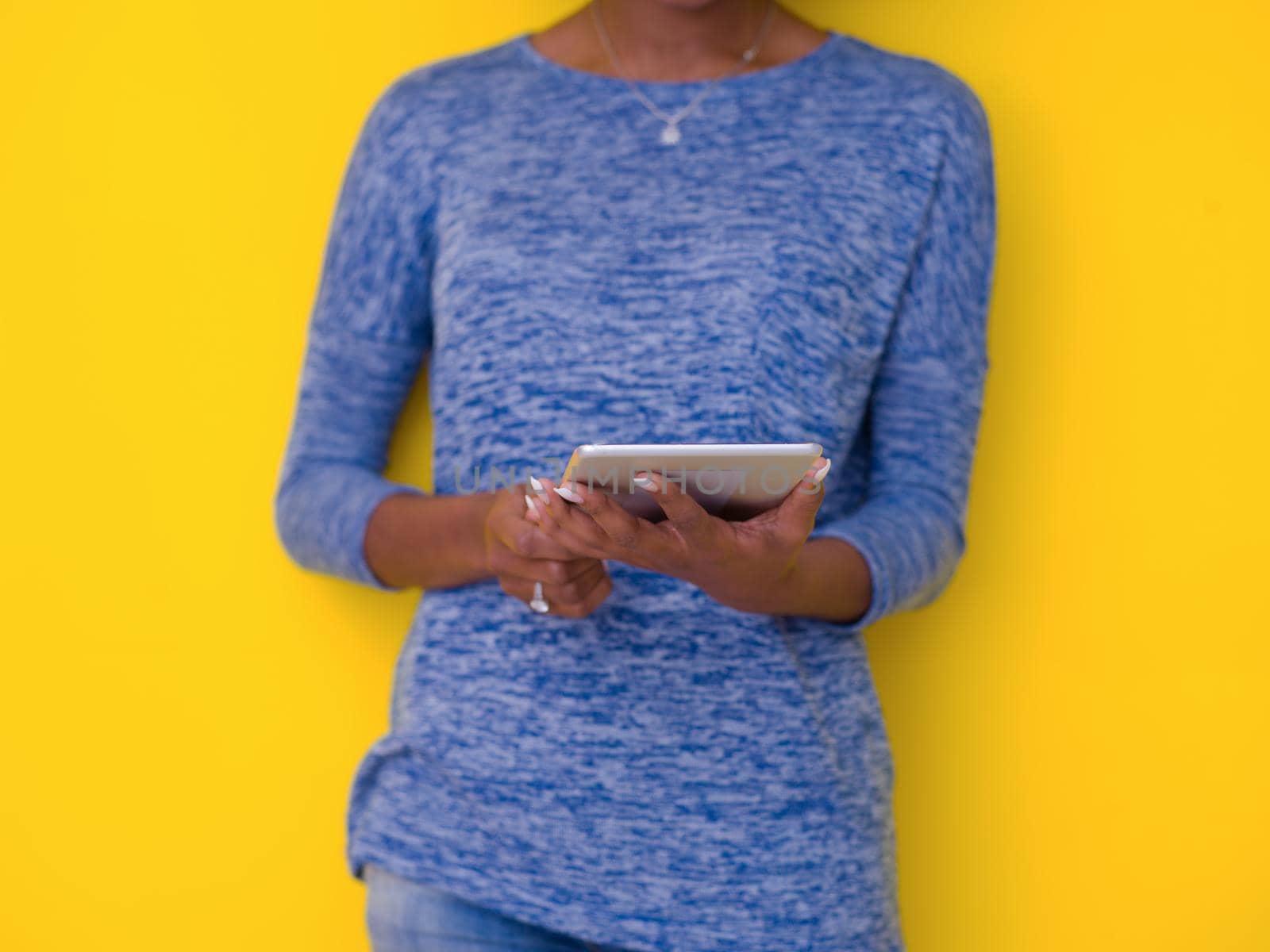 Young Happy African American Woman Using Digital Tablet  Isolated on a yellow background