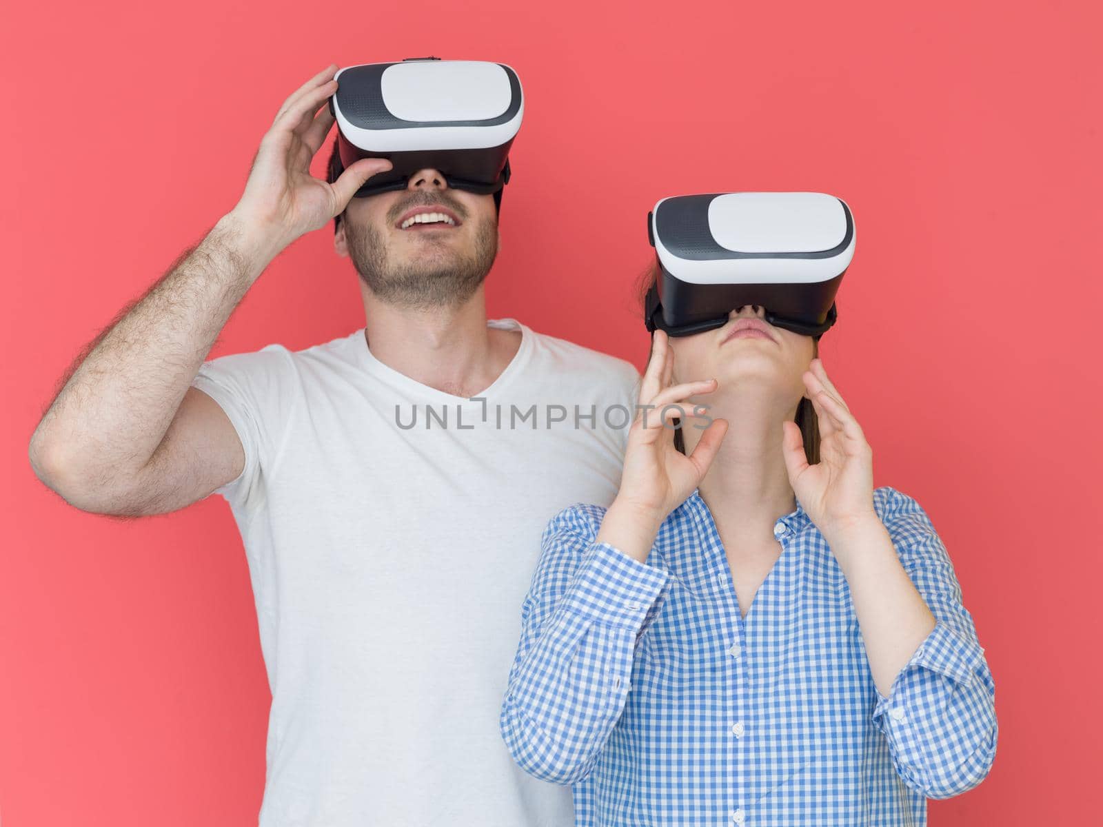 happy young couple getting experience using VR-headset glasses of virtual reality isolated over red background