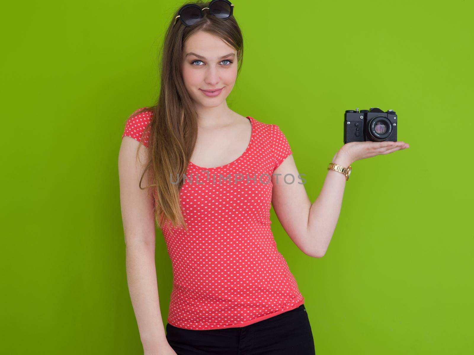 portrait of a smiling pretty girl taking photo on a retro camera isolated over green background