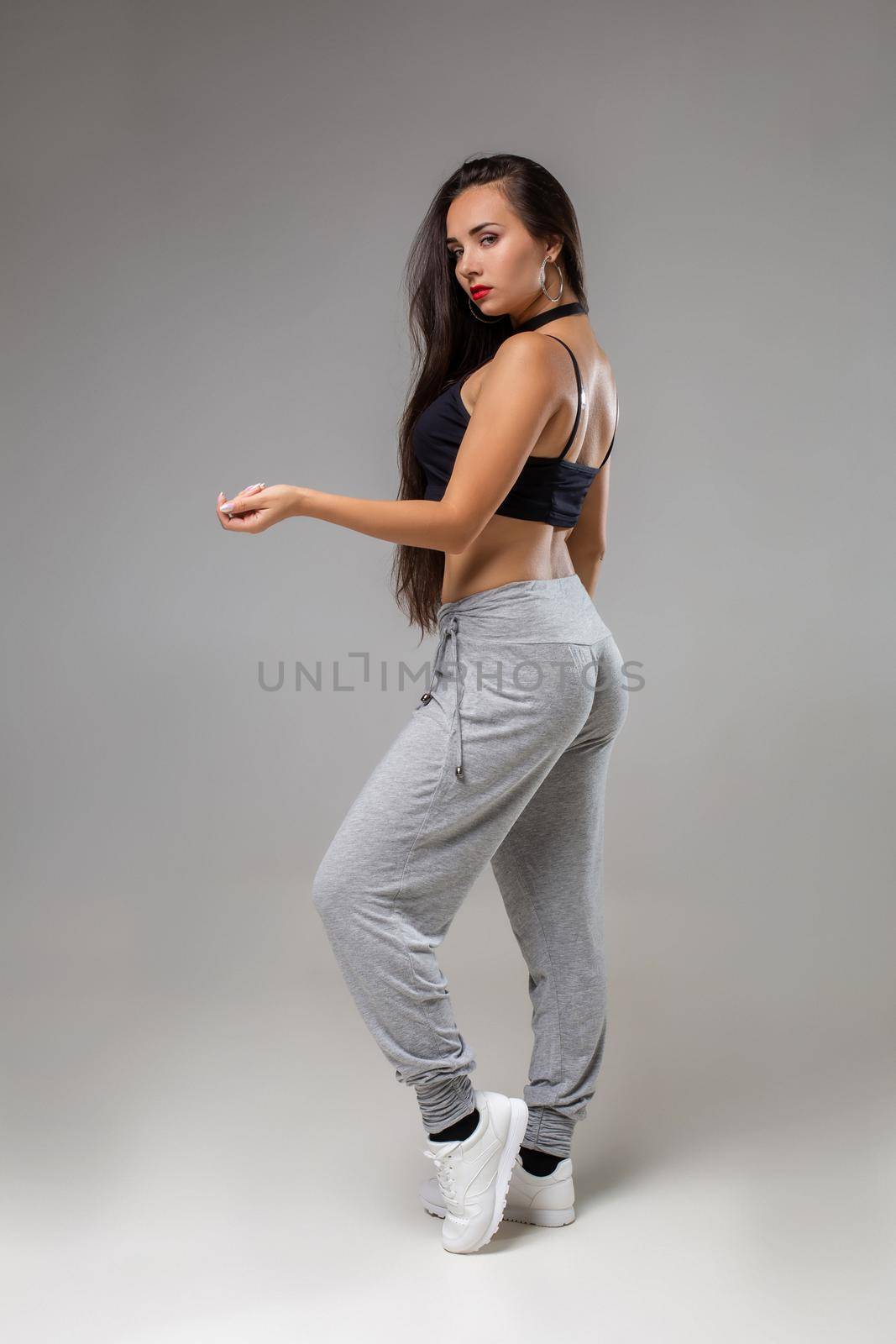 Modern dancer poses in front of the gray studio background. Modern dance styles, dancehall, jazz funk, hip hop