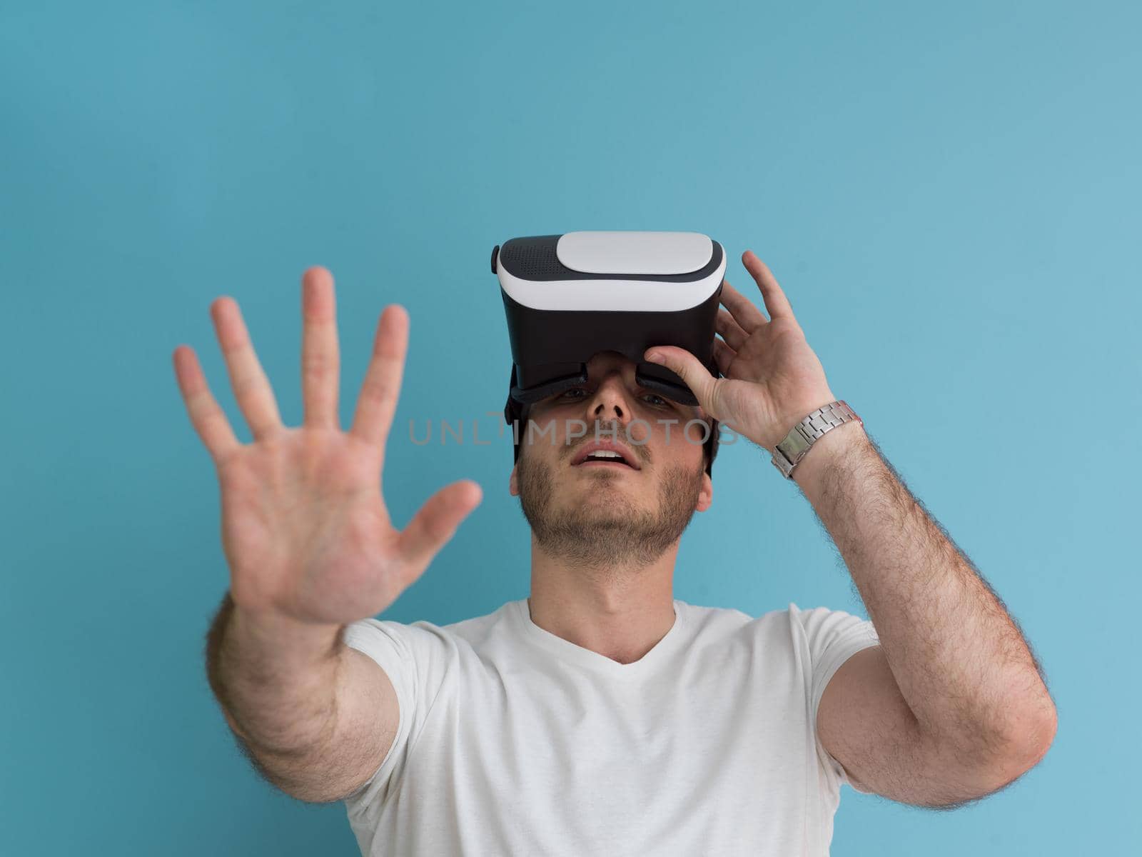 Happy man getting experience using VR headset glasses of virtual reality, isolated on blue background