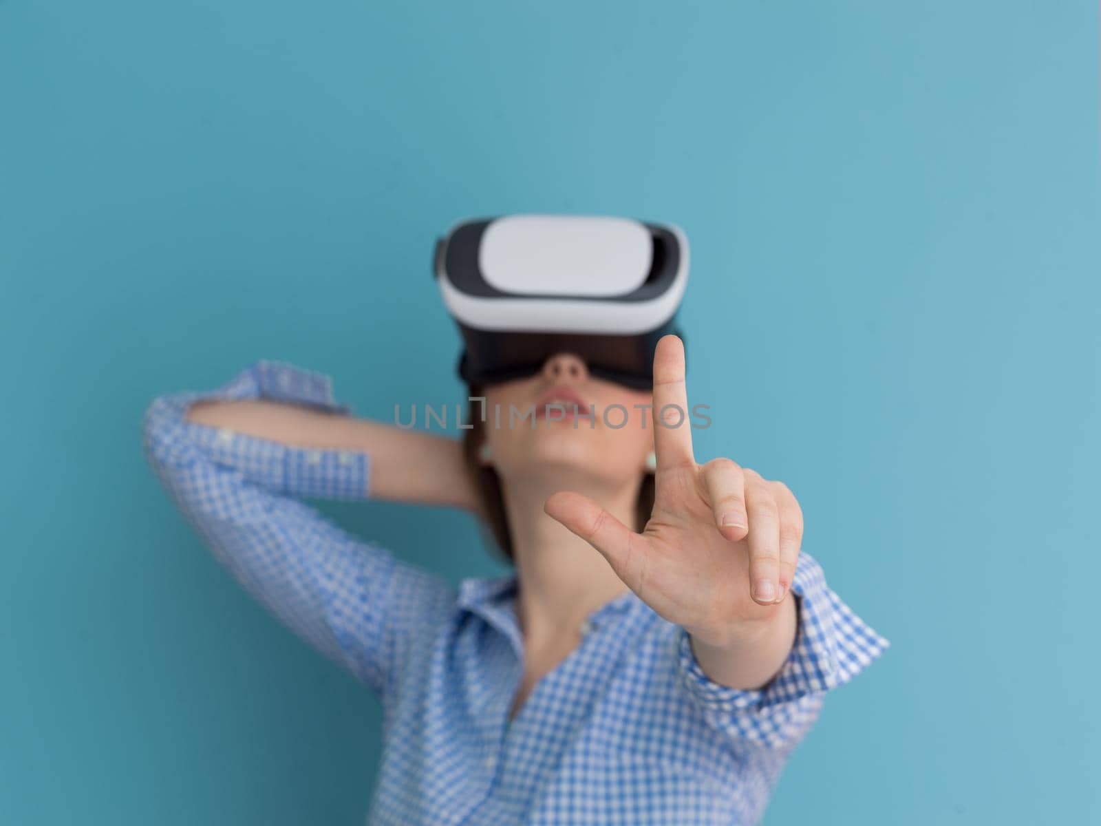 Happy girl getting experience using VR headset glasses of virtual reality, isolated on blue background