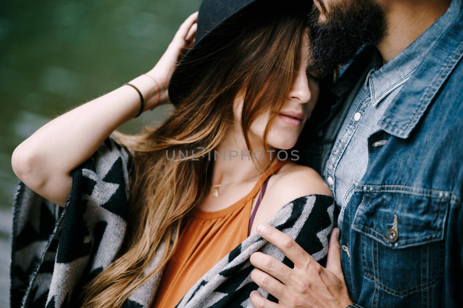 Man hugs the shoulders of a woman in hat. Portrait by Nadtochiy