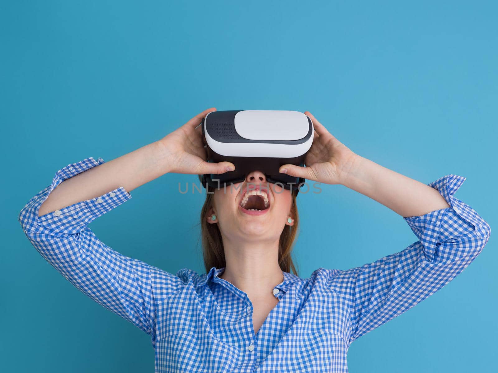 Happy girl getting experience using VR headset glasses of virtual reality, isolated on blue background