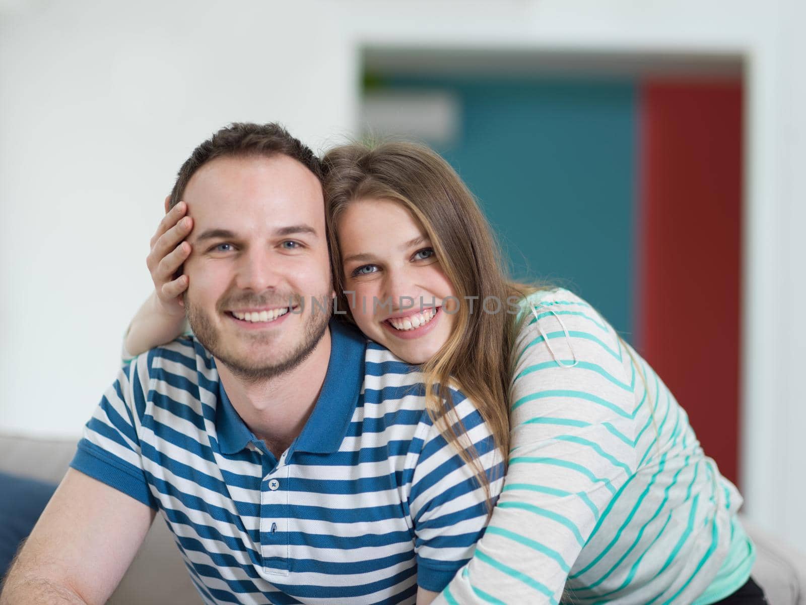 young handsome couple enjoys hugging on the sofa in their luxury home villa