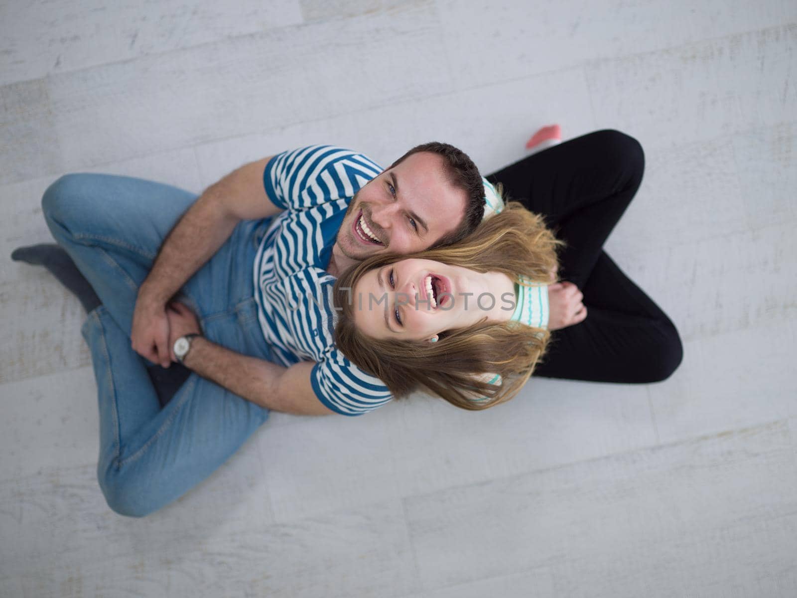 top view of Cheerful young couple sitting with back to each other on floor