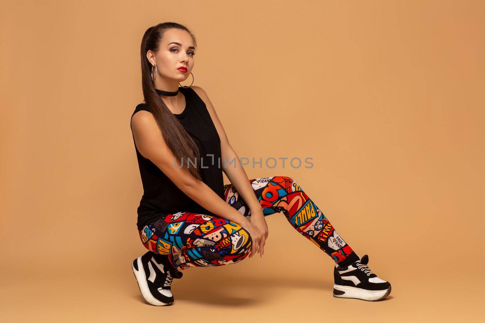 Young female dancer on studio background. Young modern style dancer girl sitting on floor in studio. Pretty female dancer of dancehall, jazz funk, hip hop