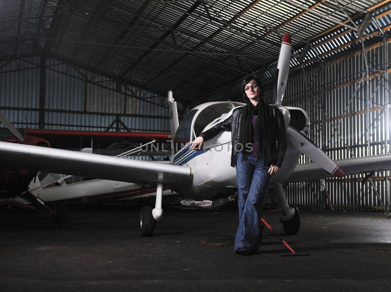 beautiful young woman model in fashion clothes posing in front of old private airplane 