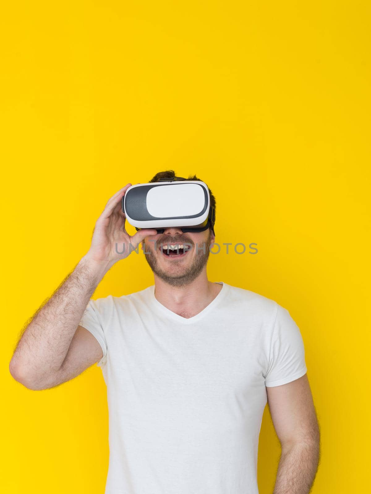 Happy man getting experience using VR headset glasses of virtual reality, isolated on yellow background